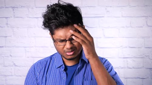 Young Man With Headache Puts Hand on Forehead