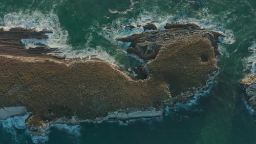 Aerial View of the Rocky Formation Washed with Greenish Sea Waves