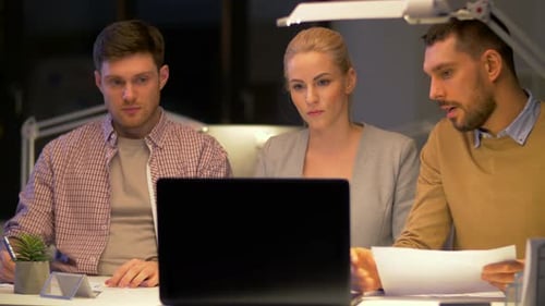 Equipe de negócios com laptop trabalhando no escritório noturno