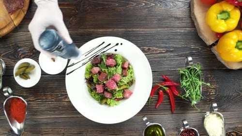 Chef Dressing a Salad on Wood Table