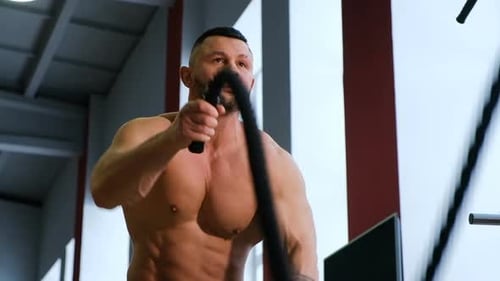 Fitness Man Doing an Intense Workout Using Ropes in a Gym. Strong Muscular Bodybuilder