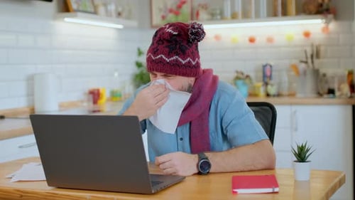 Sick Man Working on Laptop in Home Kitchen