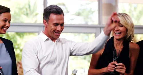 Smiling man popping a champagne bottle