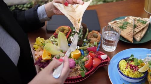 Woman enjoying vegetarian Mediterranean plate at outdoor cafe
