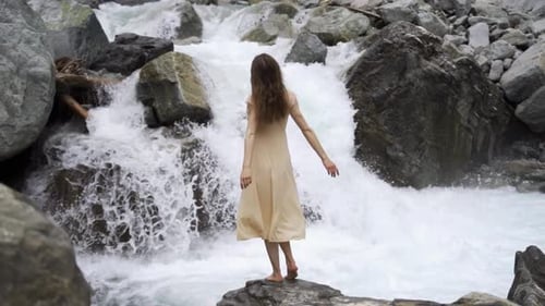Woman Stands Before a Powerful Mountain Waterfall