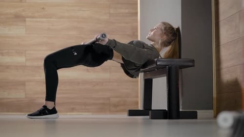 Attractive Slim Woman Is Training Muscles of Ass and Legs in Fitness Hall, Leaning on Bench By Back