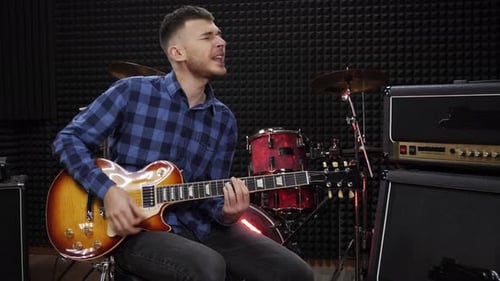 Emotional musician performs song in recording vocal studio. Playing guitar and singing