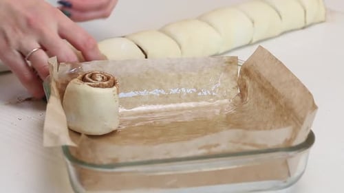 Eine Frau legt geschnittenen Teig mit Zimt in eine Auflaufform zum Backen von Zimtbonbons. Nahaufnahme.