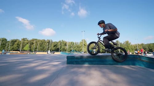 Cyclist Balances on Edge of Skatepark Ramp