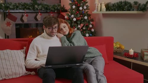 Loving Couple Using Laptop on Sofa at Christmas