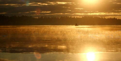 Lone Fisherman Boating on Lake at Golden Sunrise