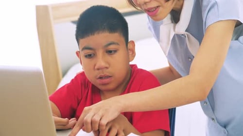 Teen in Wheelchair Works on Laptop with Assistance