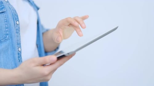 Close Up on the Hand of Young Handsome Woman Pointing and Touching the Screen of a Tablet with Her