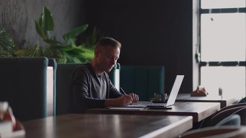Smiling Man with Works From Home in His Kitchen Using a Laptop