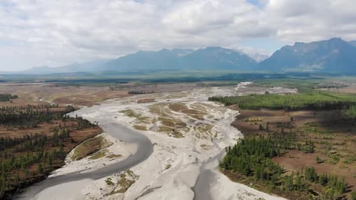 Die Drohne fliegt über den Fluss. Hohe blaue Berge im Hintergrund