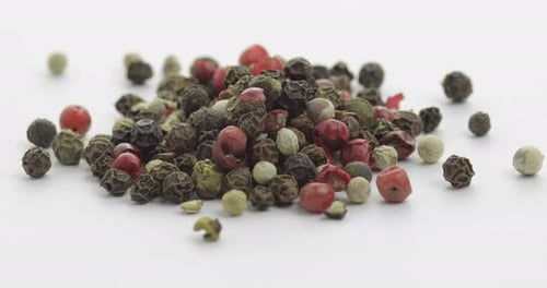 Close up of colorful peppercorns on white surface
