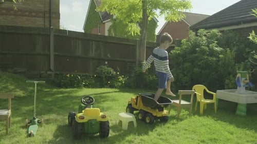 Young Child Playing on Toys in Grassy Backyard