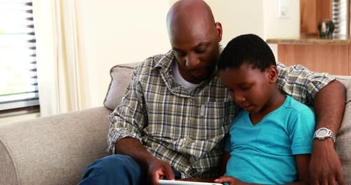 Father and Son Using a Tablet on Couch