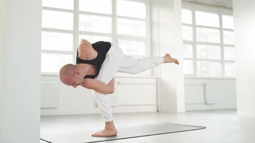 Ruhiger kaukasischer Yogi, männlich mit Glatze, halten Sie das Gleichgewicht, während Sie die Haltung auf einem Bein ausüben