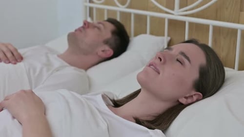 Verärgerte Frau denkt im Bett neben Schlafpartner