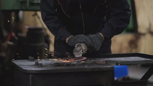Vista frontal de los trabajadores de la fábrica que utilizan herramientas para moler metales y muestran un fragmento de chispa brillante