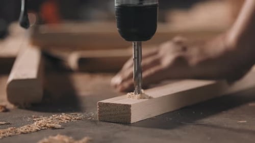 Power Drill Bores a Hole into Wood Plank