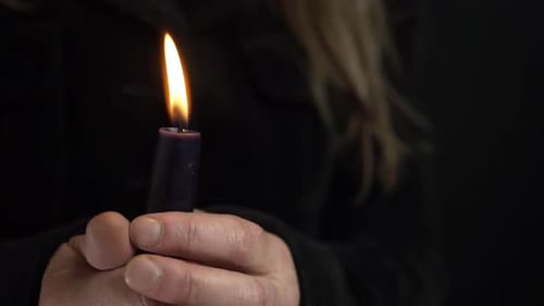 Mujer sosteniendo una vela larga para la vigilia sobre fondo oscuro tiro medio