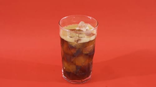 Glass of Soda With Ice on Red Background
