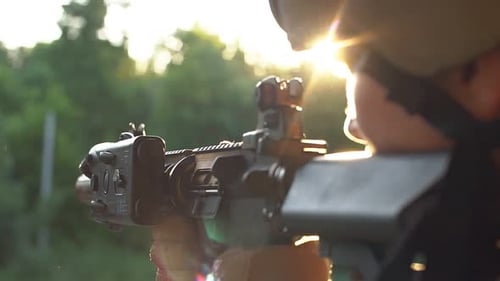 Person Holding Rifle at Sunrise in Natural Setting
