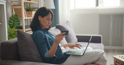 Woman Uses Laptop, Credit Card for Online Shopping