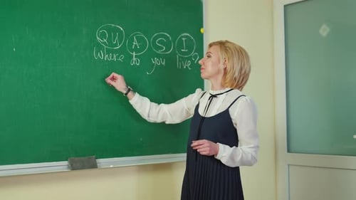 Teacher Writing on Chalkboard in Classroom