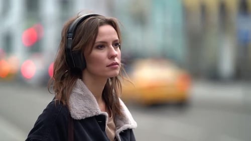 Young Townswoman with Headphones Is Standing Near Road in City at Gloomy Day, Portrait Outdoors