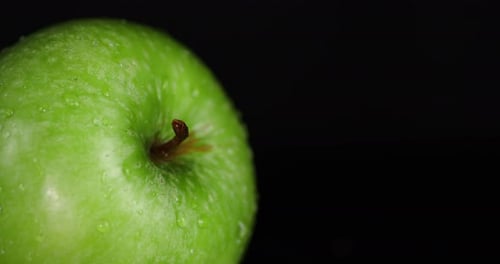 Rotierender frischer grüner Apfel mit Wassertropfen.