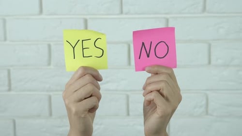 Hands Holding 'Yes' and 'No' Notes