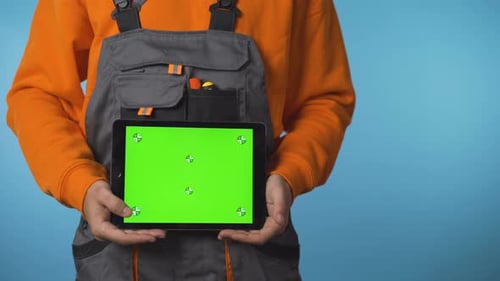 Close Shot of Construction Worker Hands Holding a Tablet with Green Screen. Commercial Ready