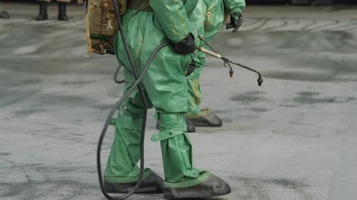 Workers in Green Protective Suits Spraying Liquid
