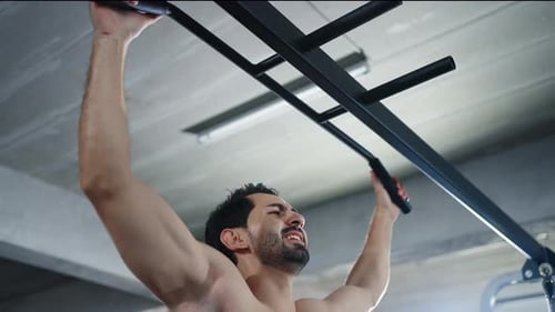 4K Caucasian man bodybuilder pulling weight lifting machine at gym.