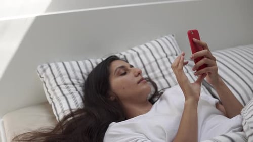 Woman Lies in Bed Using Mobile Phone