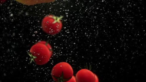 Cherry Tomatoes and Red Yellow Paprika Bell Peppers Falling Into Water with Air Bubbles