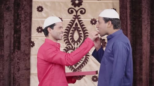 Indian man giving sweets to his friend on Eid