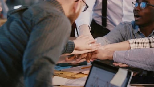 Close-up Shot of Happy Multiracial Business Partners Put Hands Together As a Team Over Office Table