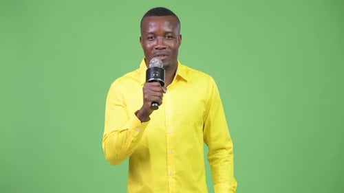 Young Happy African Businessman Presenting Something with Microphone