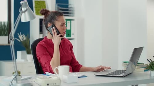 Woman Working at Desk Talking on Phone