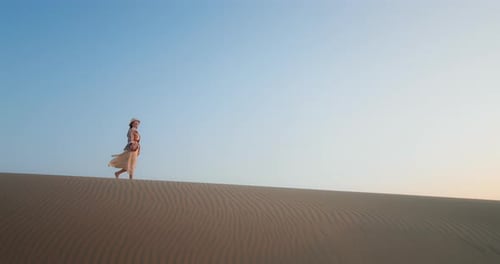Lady Walking on Sand Dune in Desert at Sunset
