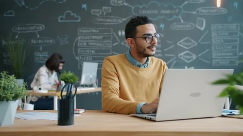 Portrait of Afro-American Man Working with Laptop in Open Space Office Typing
