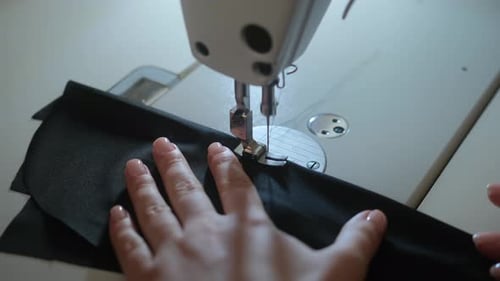 Stitching on sewing machine. Tailor sews on sewing machine. Close-up of woman's hand