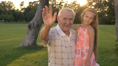 Grandfather and Granddaughter Waving in Golden Sunlight