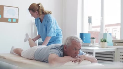 Physical Therapist Helping Senior Patient With Leg Exercise