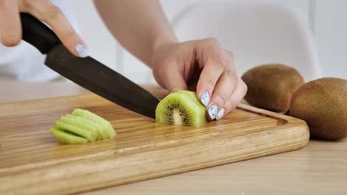 Slicing Fresh Kiwi Fruit on Cutting Board