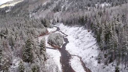 Aerial view flying over river flowing through snow covered landscape